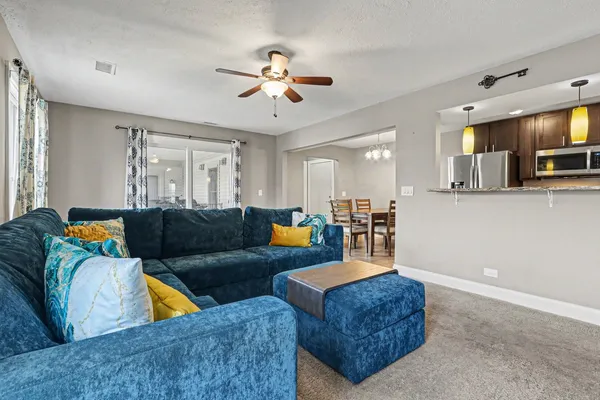 a living room with furniture kitchen view and a chandelier