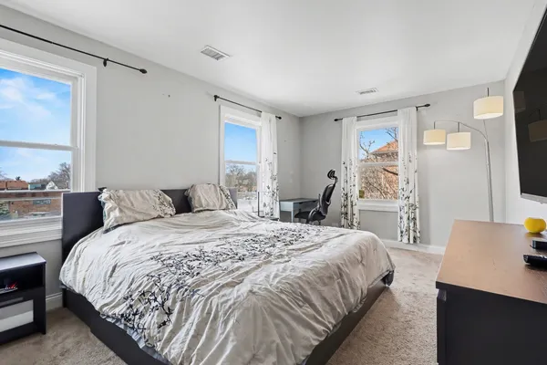 a spacious bedroom with a bed and a flat screen television
