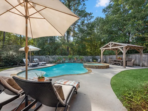 a view of a swimming pool with a table and chairs under an umbrella