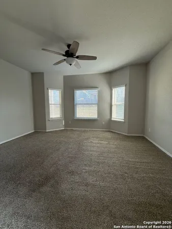 an empty room with windows and ceiling fan view