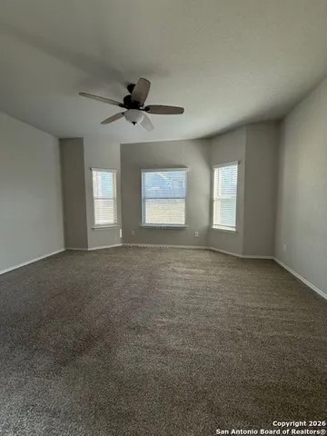 an empty room with windows and ceiling fan view