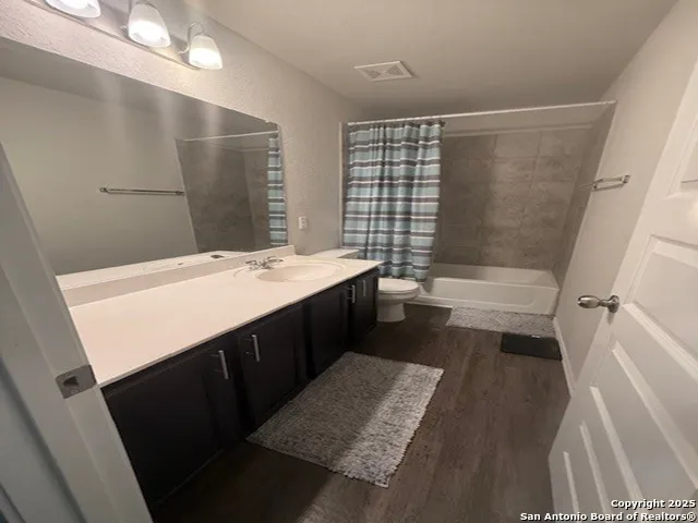 a bathroom with a sink a toilet a mirror and shower