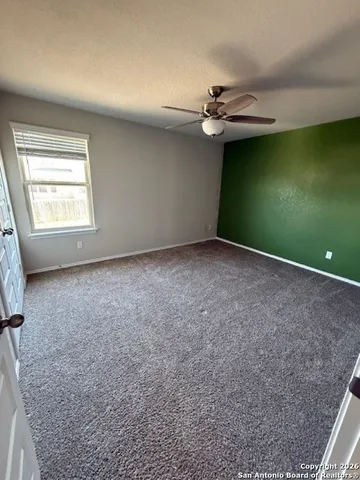 an empty room with a ceiling fan and window