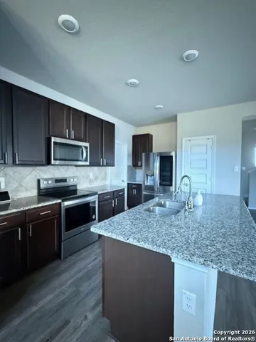 a kitchen with stainless steel appliances granite countertop a sink dishwasher stove top oven and refrigerator