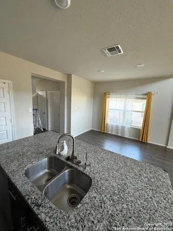 a kitchen with a sink granite counter tops and a view of living room