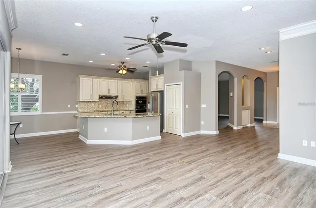 a view of kitchen with stainless steel appliances granite countertop wooden floors and white walls