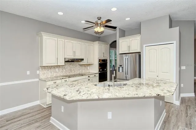 a kitchen with stainless steel appliances kitchen island granite countertop a sink dishwasher and a stove with wooden floor
