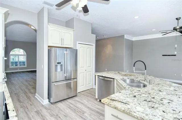 a kitchen with granite countertop a sink appliances dining table and chairs