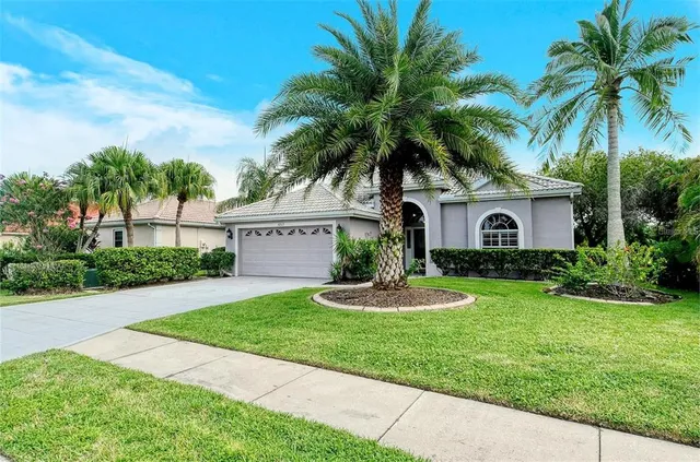 a view of a house with a yard and palm trees