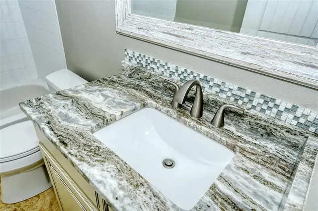 a bathroom with a granite countertop sink toilet and shower