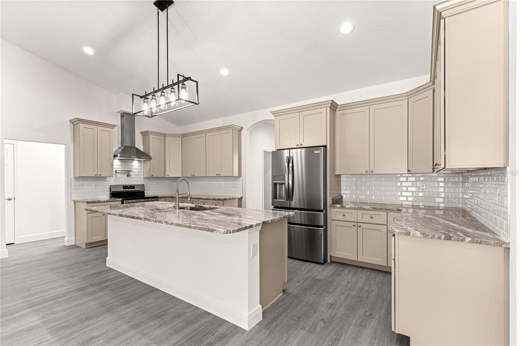 12411 Southwest 71st Lane Road Ocala, FL 34481 - Photo 12 of 50 a kitchen with stainless steel appliances granite countertop a sink a stove a refrigerator and island with wooden floor