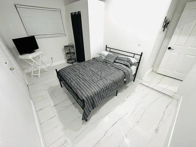 a bedroom with a bed tv and a mirror