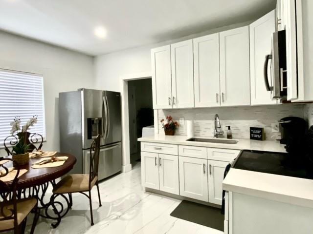 55 Northwest 47th Street Miami, FL 33127 - Photo 8 of 31 a kitchen with a refrigerator a stove a sink and white cabinets with wooden floor