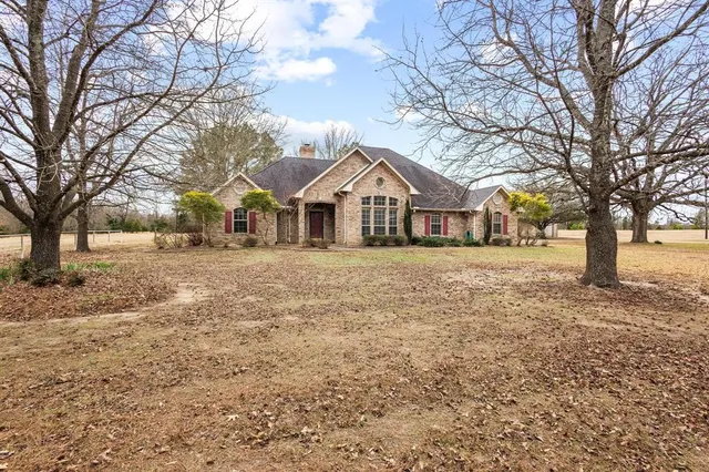 a front view of a house with a yard and large trees