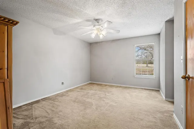 an empty room with a window and a ceiling fan