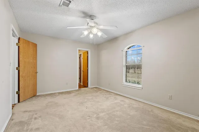 an empty room with windows and fan