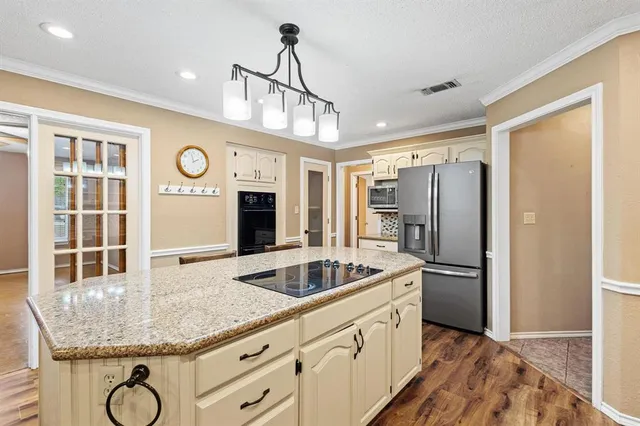 a kitchen with stainless steel appliances granite countertop a sink a refrigerator and a granite counter tops with white cabinets
