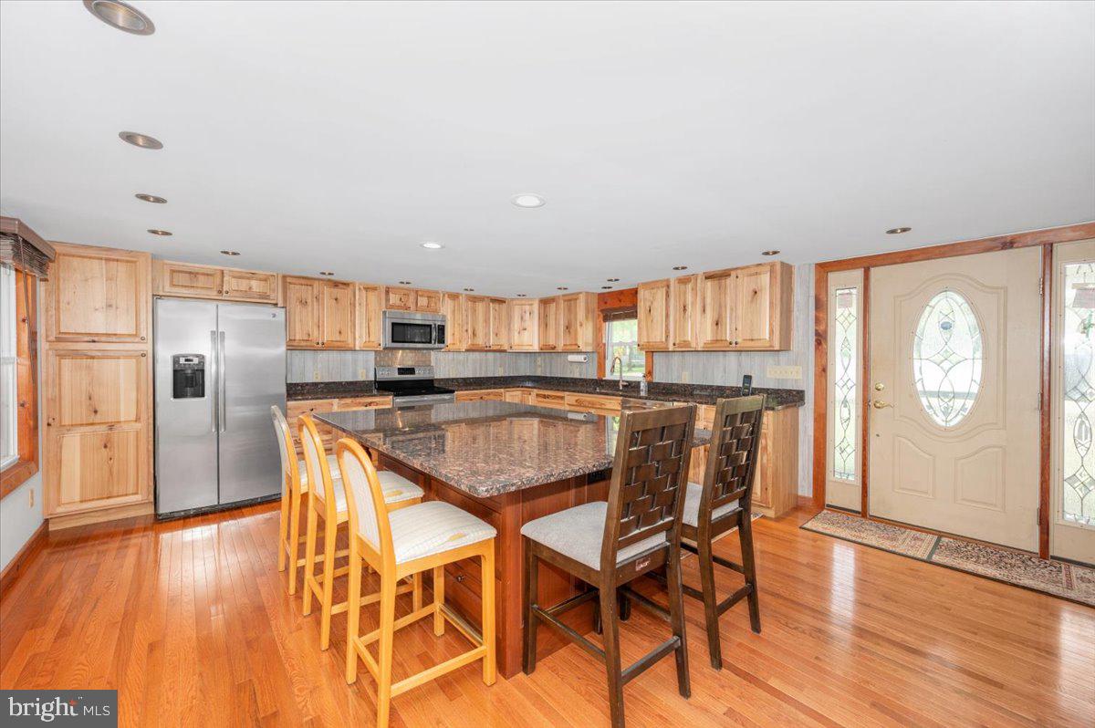 7010 Old Pryor Road Thurmont, MD 21788 - Photo 14 of 62 a kitchen with stainless steel appliances granite countertop a refrigerator a stove a sink dishwasher with a dining table and chairs with wooden floor