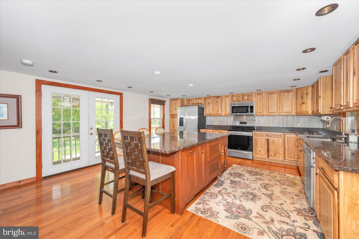 7010 Old Pryor Road Thurmont, MD 21788 - Photo 15 of 62 a large kitchen with stainless steel appliances granite countertop a stove top oven a sink dishwasher and cabinets with wooden floor