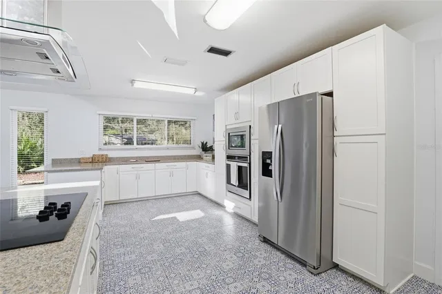 a large white kitchen with granite countertop a refrigerator and a stove