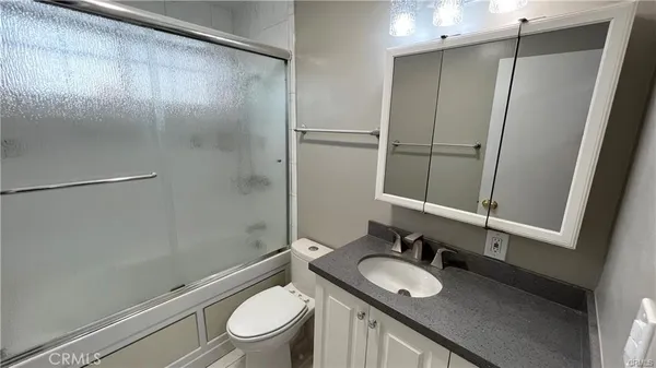 a bathroom with a granite countertop sink toilet and shower