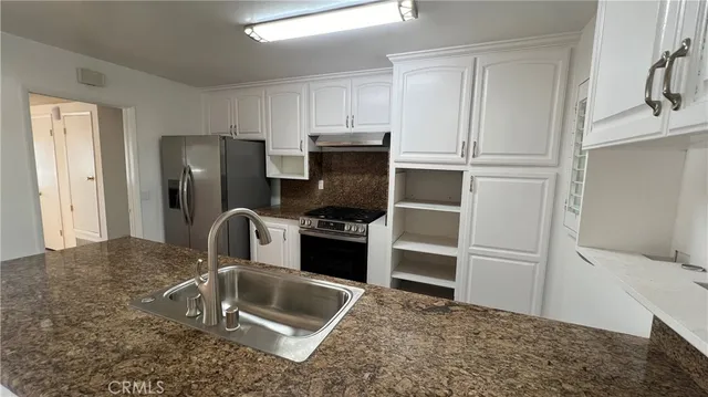 a kitchen with granite countertop a refrigerator and a sink