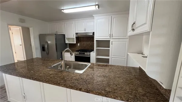 a kitchen with stainless steel appliances granite countertop a sink a stove and refrigerator