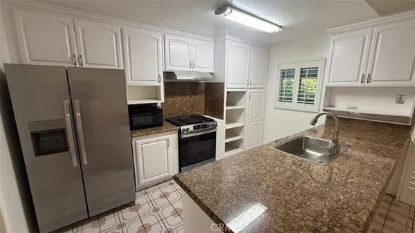 a kitchen with stainless steel appliances granite countertop a refrigerator stove and sink