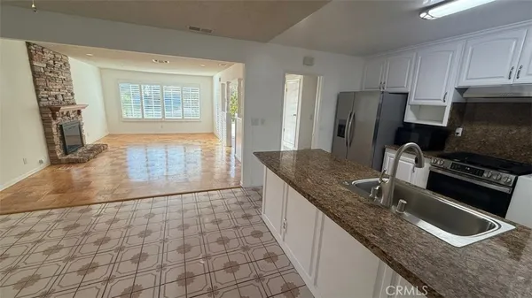 a kitchen with granite countertop a sink a stove a microwave a refrigerator and cabinets