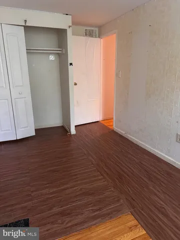 a view of an empty room with wooden floor and a cabinet