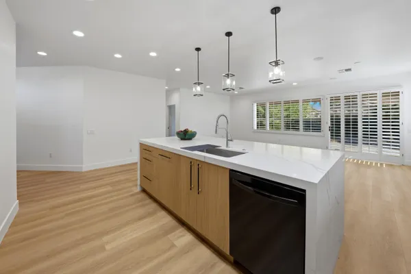 a kitchen with stainless steel appliances granite countertop a sink a oven and a wooden floor