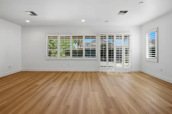 a view of an empty room with a window and wooden floor