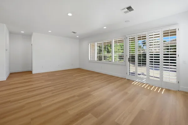 a view of kitchen and empty room with wooden floor