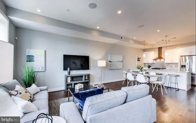 a kitchen with stainless steel appliances granite countertop a refrigerator a sink dishwasher a stove and a dining table with wooden floor