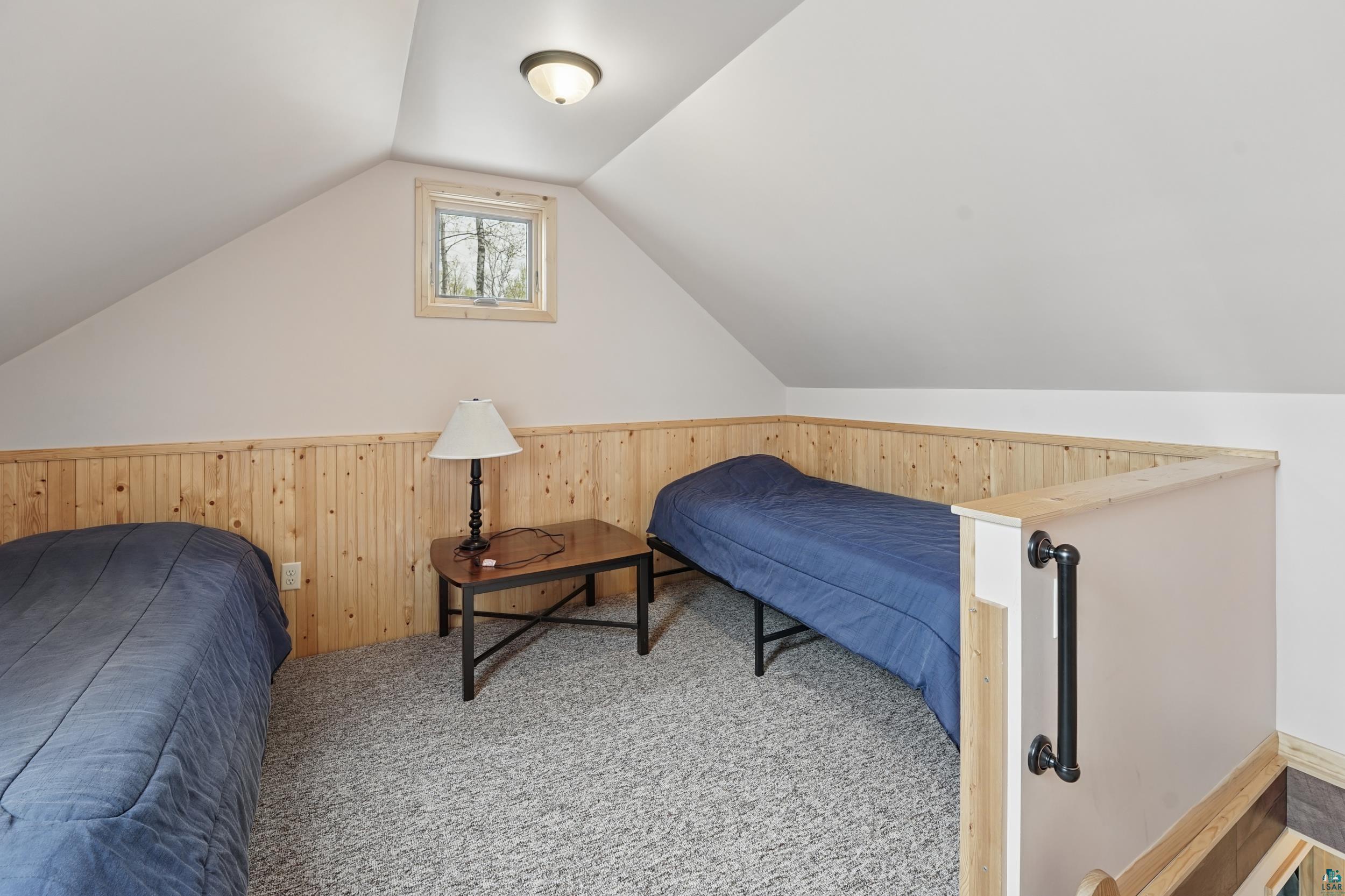 89095 West Romans Point Road Herbster, WI 54844 - Photo 22 of 30 Attic room featuring sloped ceilings, light wood paneling, a single window, and textured carpet flooring