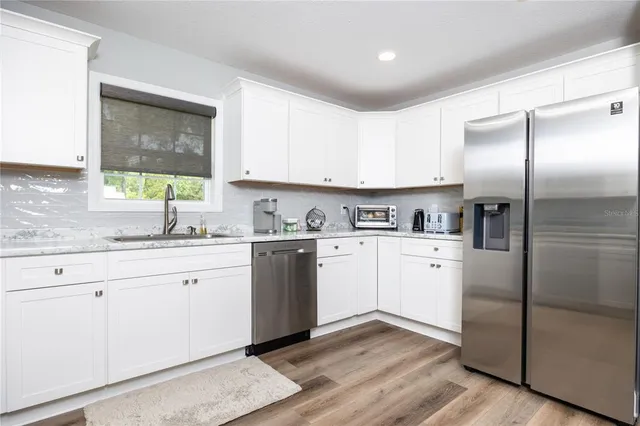 a kitchen with stainless steel appliances granite countertop a refrigerator sink and window