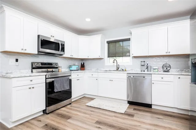 a kitchen with granite countertop white cabinets and white appliances