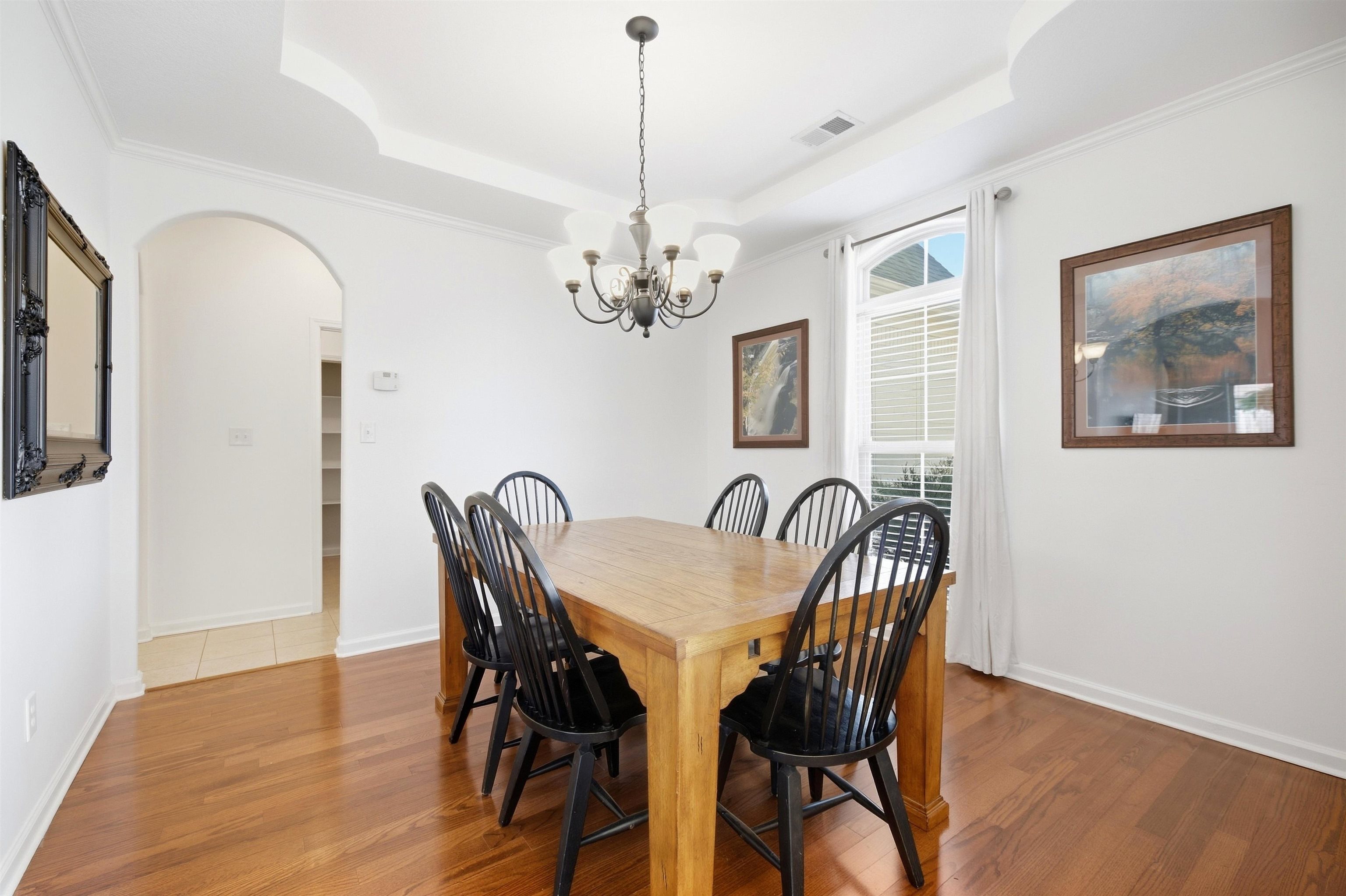 7920 Pips Ridge Lane Bartlett, TN 38133 - Photo 21 of 40 Hardwood flooring, tray ceiling with crown molding, arched entry, and a multi-pane window with blinds