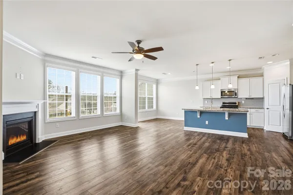 a living room with stainless steel appliances kitchen island granite countertop a stove a refrigerator a sink a dining table and chairs with wooden floor