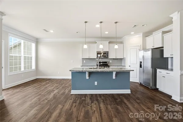a kitchen with stainless steel appliances granite countertop a refrigerator a sink dishwasher a stove and white countertops with wooden floor