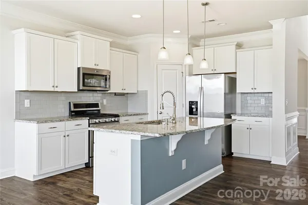 a kitchen with stainless steel appliances granite countertop a refrigerator a stove a sink and white cabinets