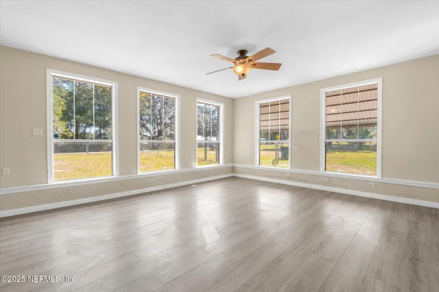 a view of an empty room with a window and wooden floor
