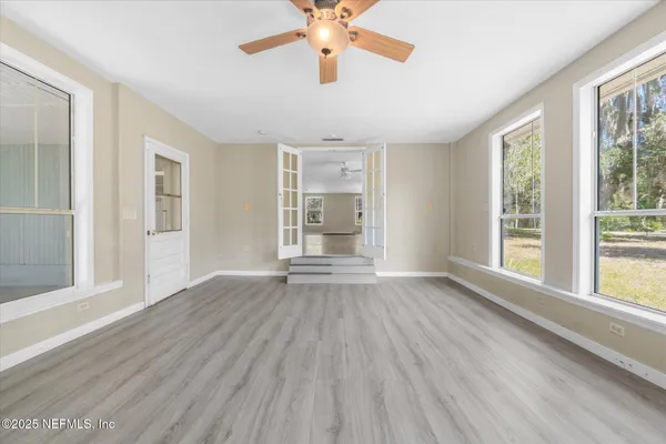 a view of an empty room with wooden floor and a window