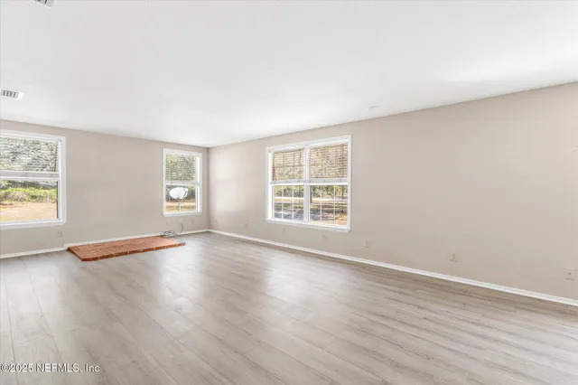 an empty room with wooden floor and windows