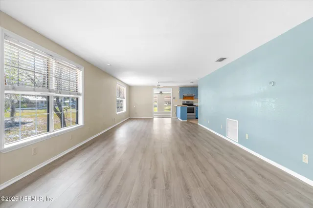 a view of empty room with wooden floor and fan