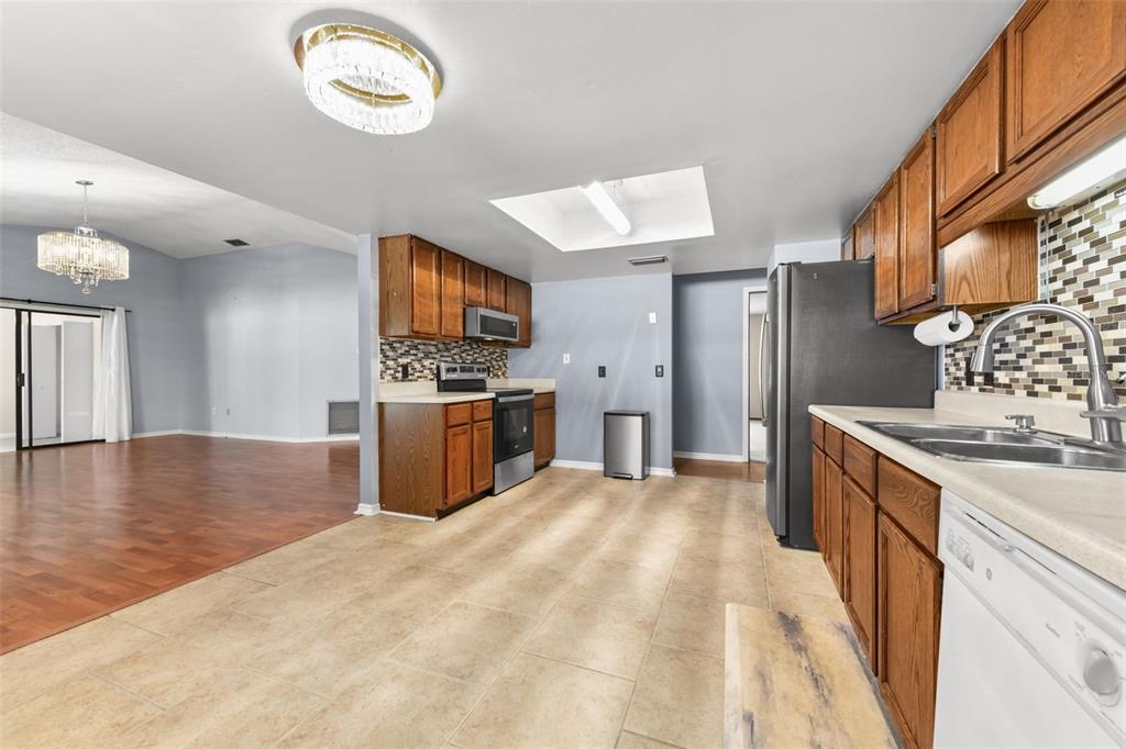 1580 East Normandy Boulevard Deltona, FL 32725 - Photo 14 of 46 a large kitchen with stainless steel appliances granite countertop a sink dishwasher stove and a refrigerator with wooden floor