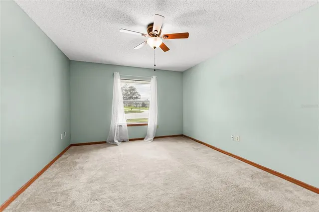 an empty room with window and ceiling fan