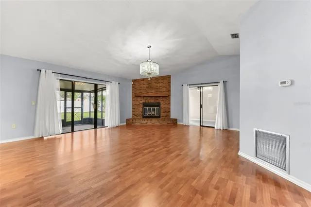 a view of an empty room with window and wooden floor
