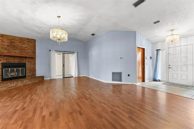 a view of an empty room with a fireplace and wooden floor