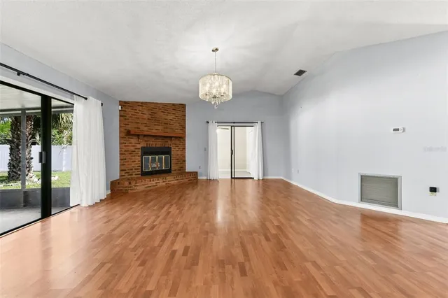 an empty room with wooden floor fireplace and windows